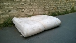A forlorned mattress that has been abandoned in the street.